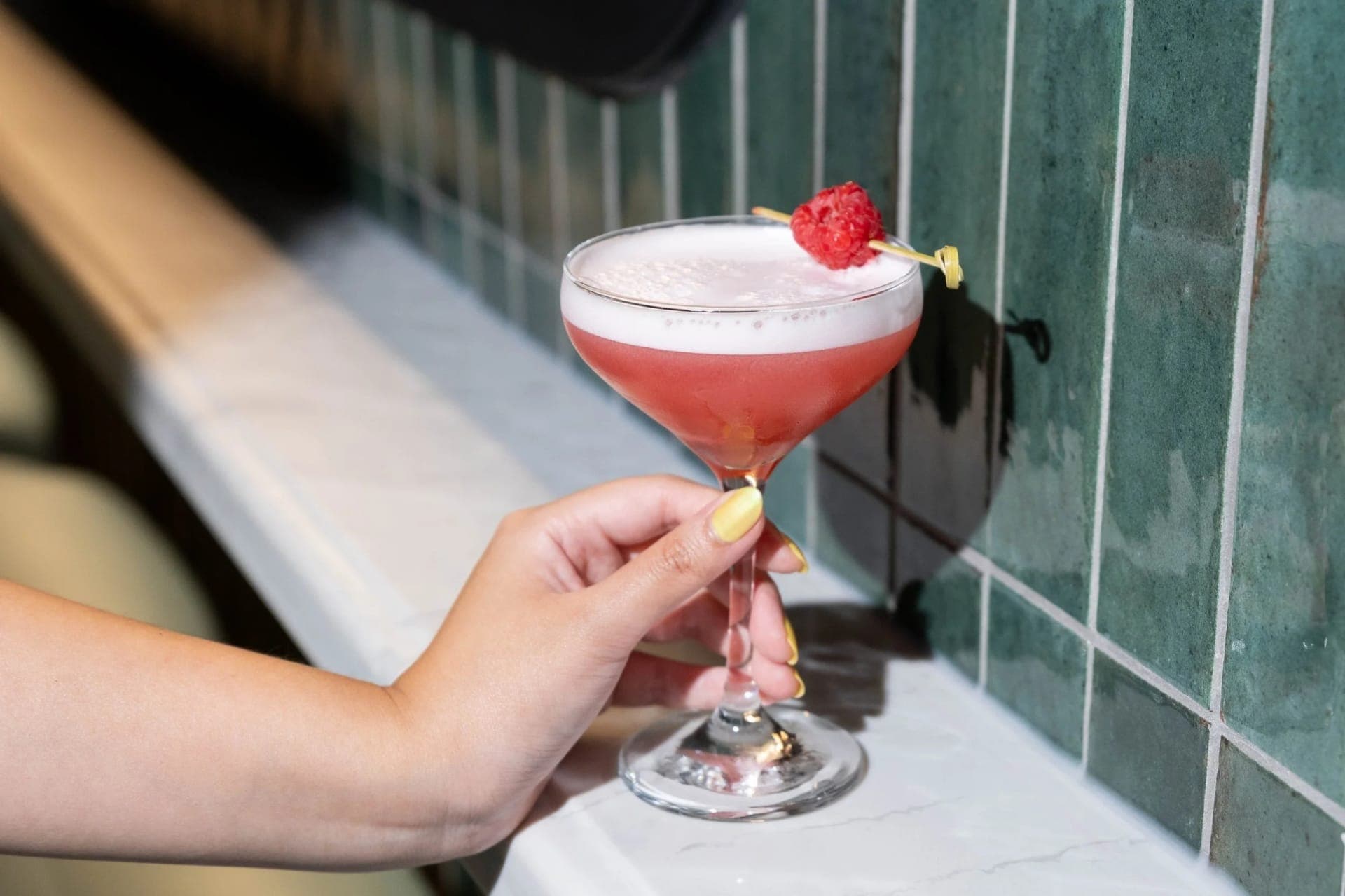 A Clover Club cocktail in hand at the bar